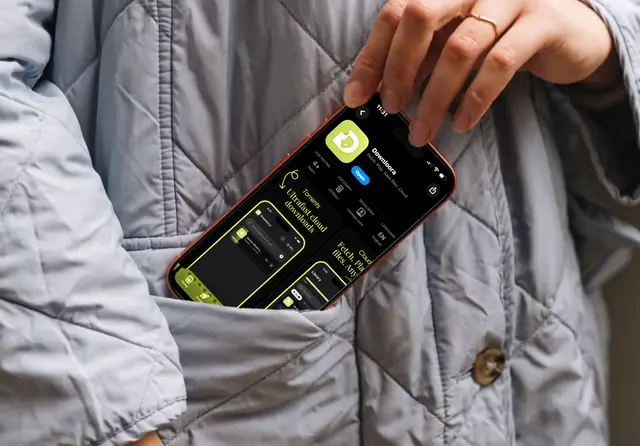 An iPhone displaying Downloora being placed in a jacket pocket